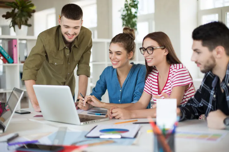 young-positive-business-people-joyfully-working-laptop-together-group-smiling-men-women-spending-time-work-modern-cozy-office